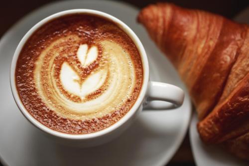 a cup of coffee on a plate with a croissant at La Locanda di Decima in Castel di Decima