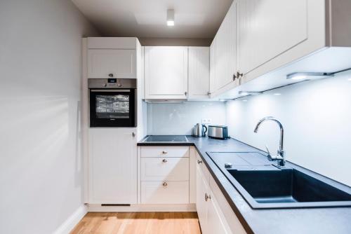 a kitchen with white cabinets and a sink at Kamphof Usedom Ferienanlage in Loddin