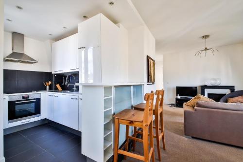 une cuisine avec des armoires blanches et une table et des chaises dans l'établissement Belle vue, à Levallois-Perret