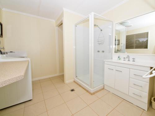 a white bathroom with a shower and a sink at Charleville Bush Cottage in Charleville