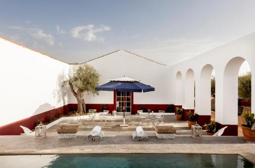 - une cour avec une piscine, des chaises et un parasol dans l'établissement Quinta da Chaminé, à Ferreira do Alentejo
