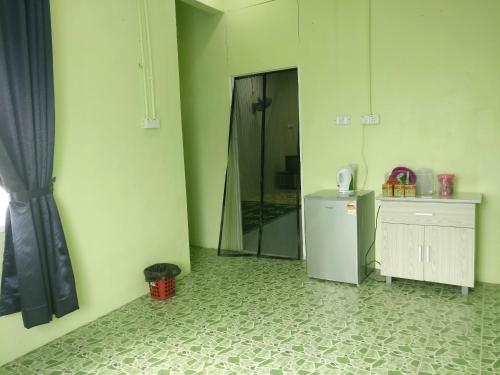 a green room with a refrigerator and a mirror at Arau Guest House in Arau