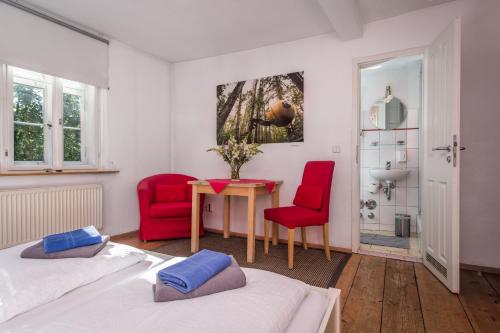 a bedroom with two beds and a table and two red chairs at "goethezimmer" Ferienwohnung und Zimmer am Burgplatz in Weimar
