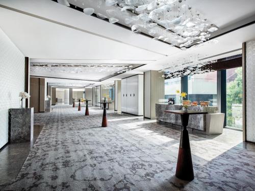a lobby with a long hallway with tables and windows at Cordis Shanghai Hongqiao (Langham Hospitality Group) in Shanghai