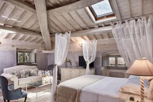 a bedroom with a bed and a couch and a window at Villa di Piazzano - Small Luxury Hotels of the World in Cortona