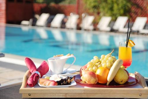 a tray of fruit and vegetables on a table next to a pool at Silver Hotel in Oradea