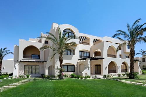 un grand bâtiment blanc avec des palmiers devant lui dans l'établissement Jaz Makadi Saraya Palms, à Hurghada