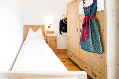 a bedroom with a bed and a dress hanging on a wall at B&B Pizzeria Zur Traube in Montagna