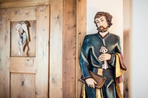 a statue of a man standing next to a wall at B&B Pizzeria Zur Traube in Montagna