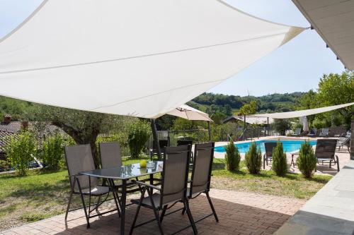 a table and chairs under an umbrella next to a pool at Guest House Valentincic in Nova Gorica