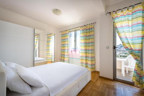 a bedroom with a white bed and a window at Apartments Montreal in Budva