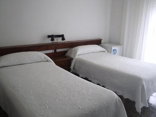 a hotel room with two beds and two night stands at Pensión K-Hito in Santiago de la Ribera