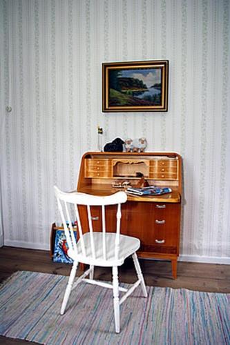 a white chair in front of a wooden desk at Smultronboda Fårgård in Edsbruk