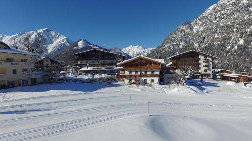 a ski lodge in the snow with mountains in the background at Appartements Fortuna in Pertisau