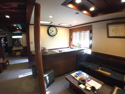 a living room with a couch and a clock on the wall at Kadokyu Ryokan in Takaoka