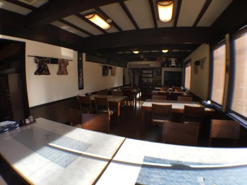 a dining room with tables and chairs and windows at Kadokyu Ryokan in Takaoka