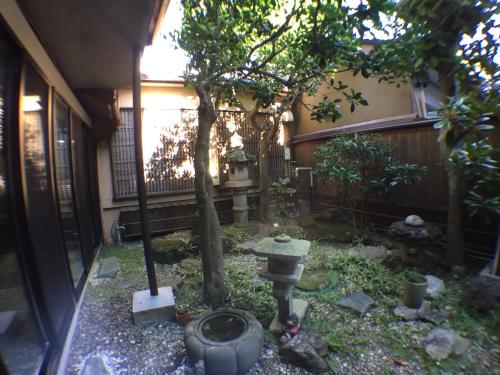 a small garden with a tree and a fence at Kadokyu Ryokan in Takaoka