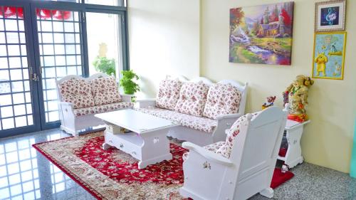 a living room with white furniture and a table and chairs at Loyofun in Donggang