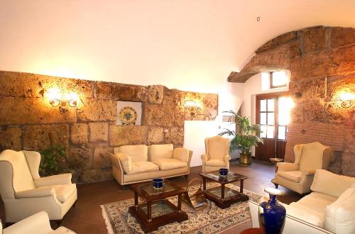 a living room with white furniture and a stone wall at Hotel&Ristorante Miramonti Palazzo Storico in Rieti