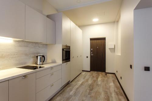 a kitchen with white cabinets and a wooden floor at Old Town Trio Apartments in Vilnius