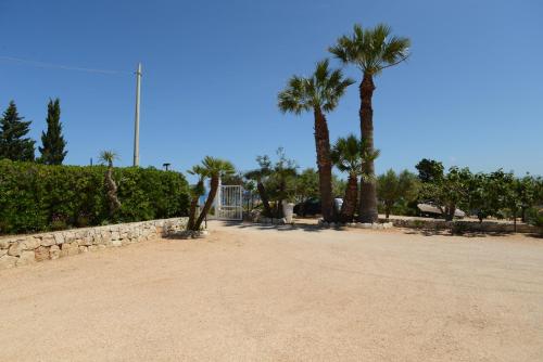 a park with palm trees and a stone wall at Kòre rooms in Castellammare del Golfo