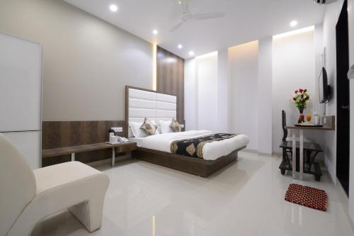 a bedroom with a bed and a desk and a chair at Hotel One Up in Ahmedabad