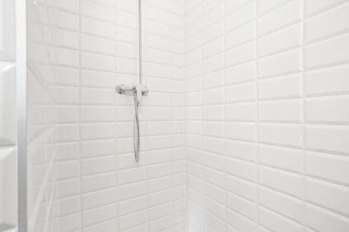 an umbrella is hanging in a white tiled shower at Aparts Sopot in Sopot