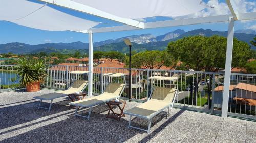 a patio area with chairs, tables and umbrellas at Hotel Tiffany in Marina di Massa