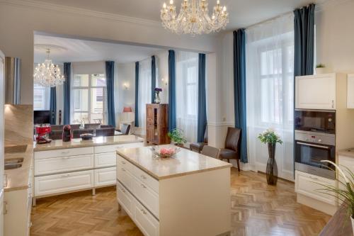 a large kitchen with white cabinets and a table at Smetanovo nábřeží 26 - Riverview Old Town Apartment in Prague