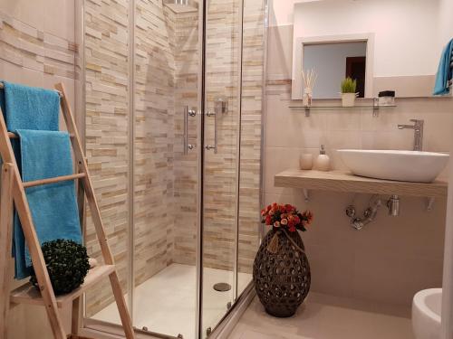 ジャルディーニ・ナクソスにあるMartin Holiday Apartmentsのガラスのシャワーと洗面台を備えたバスルーム