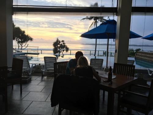 a man and woman sitting at a table looking out at the ocean at Twenty-Two Weligambay in Weligama