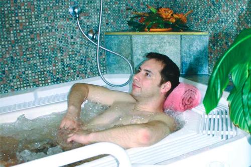 Un uomo steso in una vasca da bagno di Hotel Hochland a Leutasch