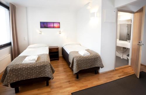 Pokój hotelowy z 2 łóżkami i lustrem w obiekcie Hotel Alvariini w mieście Alajärvi