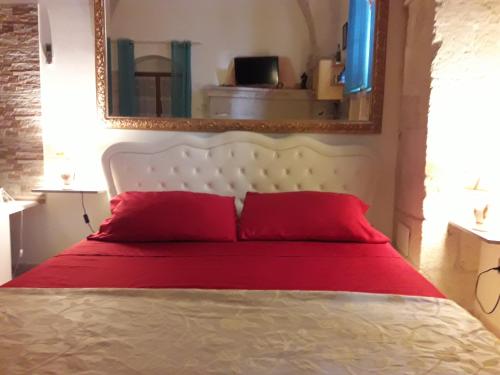 Schlafzimmer mit einem Bett mit roten Kissen und einem Spiegel in der Unterkunft L'antico palazzo in Andrano