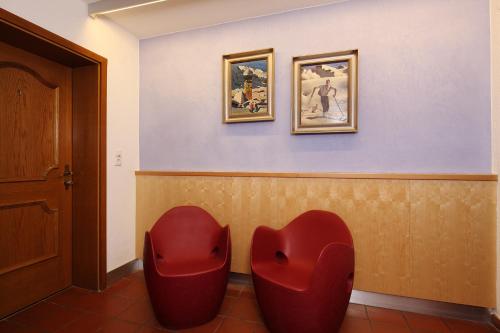 a waiting room with red chairs and paintings on the wall at Kristiania in Sölden