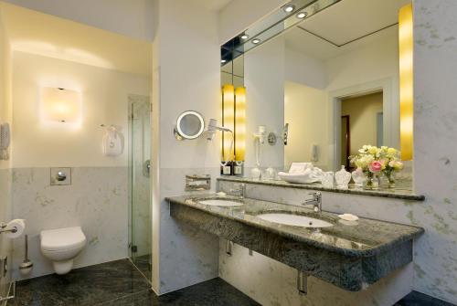 ein Badezimmer mit einem Waschbecken, einem WC und einem Spiegel in der Unterkunft Hotel Louis C. Jacob in Hamburg
