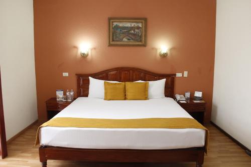 - une chambre avec un grand lit et des oreillers jaunes dans l'établissement Best Western Hotel Madan, à Villahermosa