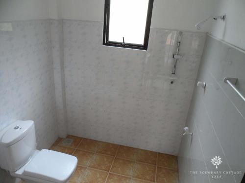 a bathroom with a toilet and a shower and a window at The Boundary Yala in Kataragama