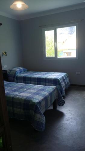 
a bedroom with two beds and a window at Hostel Los Viajeros in El Chalten
