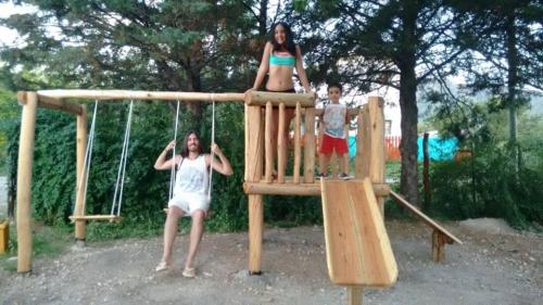 a woman and two children playing on a playground at Cabañas Esferas de Cristal in Capilla del Monte