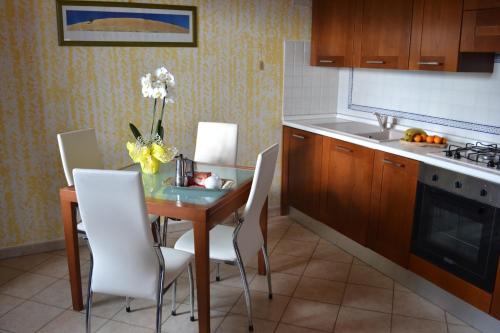 a kitchen with a table with white chairs and a sink at Appartamento panoramico in Pancole
