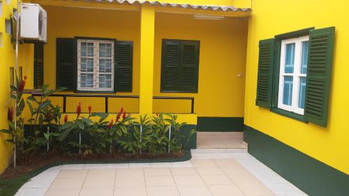 a yellow house with black windows and plants at Residencialdes in São Tomé