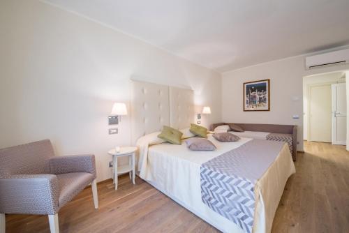 a bedroom with a large bed and a chair at Hotel Il Palazzo in Assisi