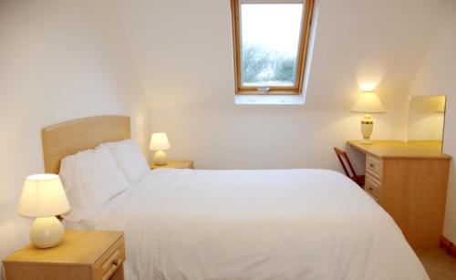 1 dormitorio con cama blanca y ventana en Burren Way Cottages, en Ballyvaughan