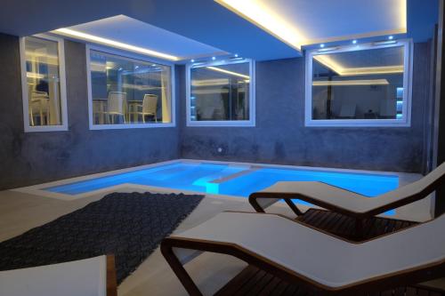 a room with a swimming pool with a chair and windows at La Dimora delle Fate Luxury & SPA in Miggiano