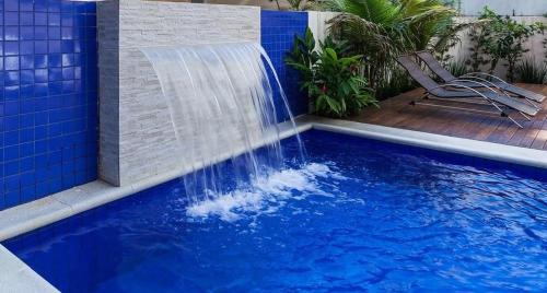 uma cascata numa piscina com azulejos azuis em Flat Guaruja Diferenciado no Guarujá