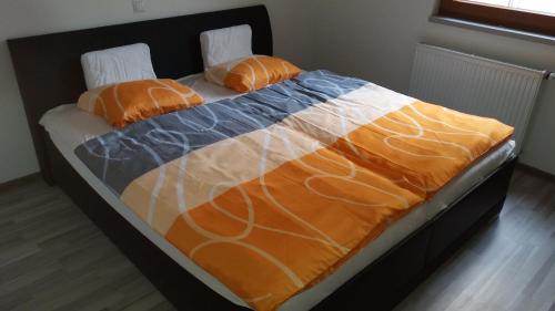 プラハにあるQuiet Apartment near to O2 Arenaのベッド1台(オレンジとブルーの掛け布団、枕2つ付)