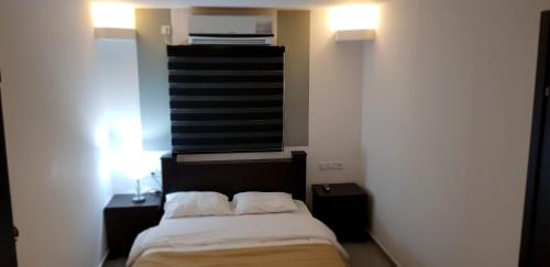 a bedroom with a bed with two night stands and a window at City Apartments in Eilat
