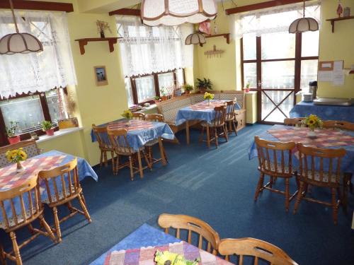 a dining room with tables and chairs and windows at Pension Borůvka in Špindlerův Mlýn