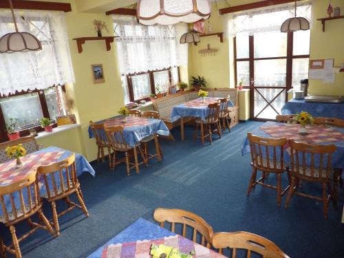 un comedor con mesas, sillas y ventanas en Pension Borůvka, en Špindlerův Mlýn